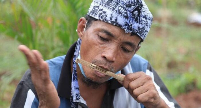 Seorang pria memainkan alat musik karinding. (Foto: Istimewa/tangerangkota.go.id)